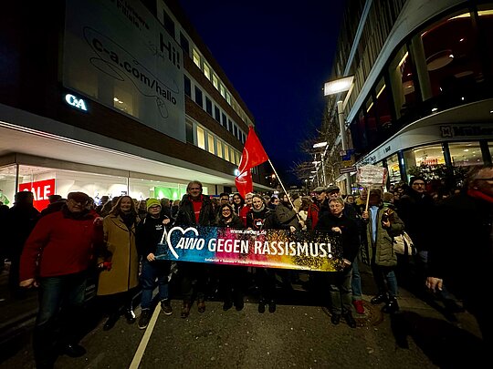 Eine Gruppe von Menschen geht mit einem Transparent mit der Aufschrift "AWO gegen Rassismus" durch eine Straße in Mönchengladbach.
