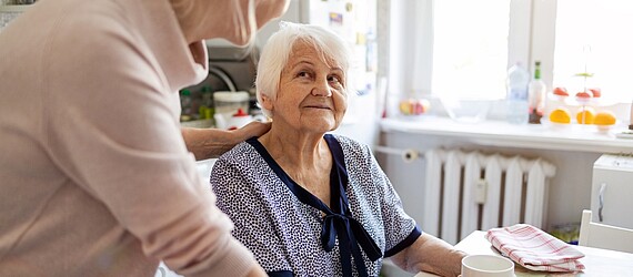 Eine Mitarbeiterin der AWO Mönchengladbach hilft einer älteren Frau in der Küche.