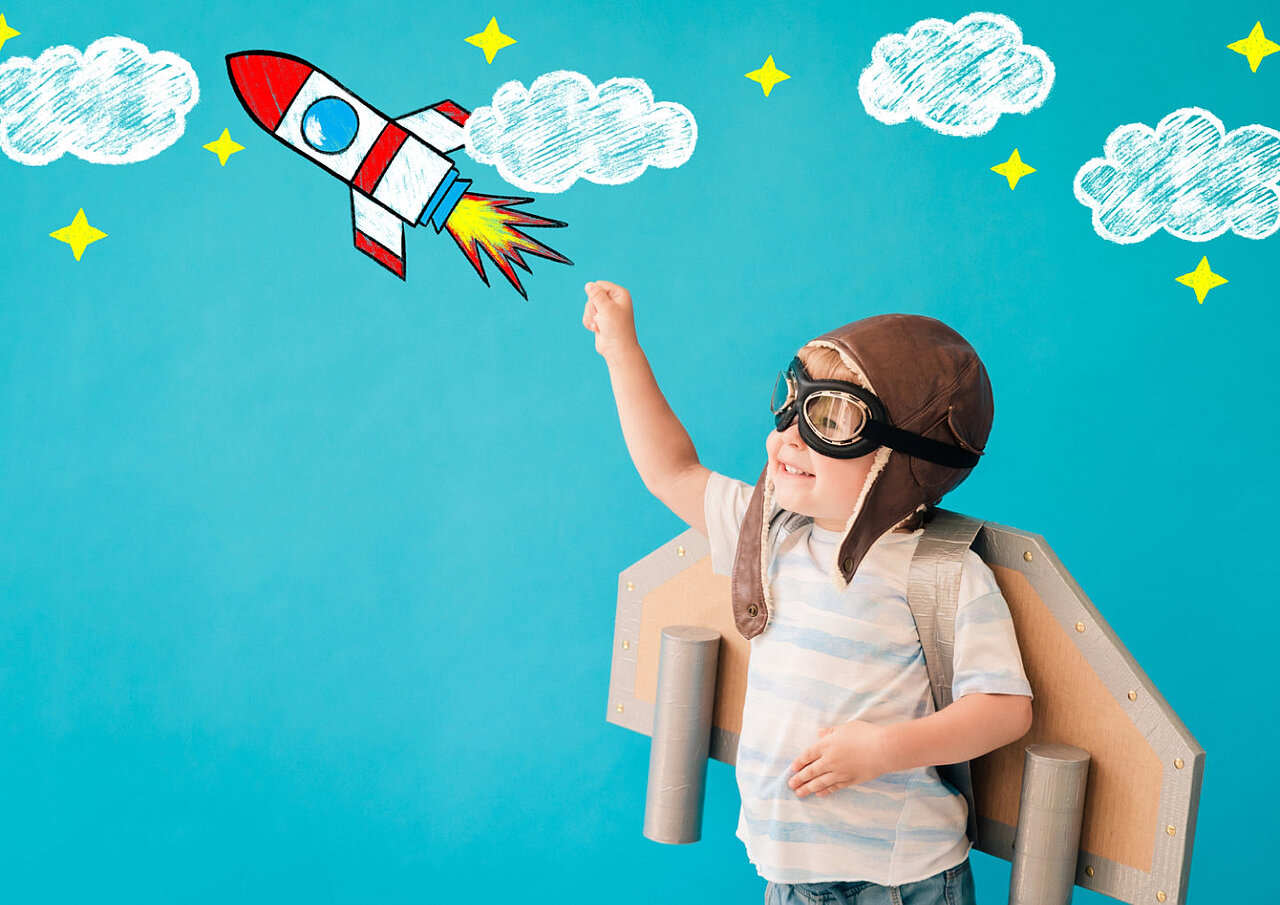 Ein als Rakete verkleideter Junge zeigt in den Himmel bei einer AWO-Kitas-Veranstaltung.