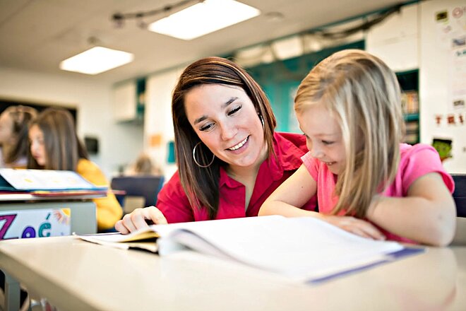 Ein Lehrer hilft einem kleinen Mädchen in einem Klassenzimmer.