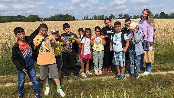 Eine Gruppe Kinder posiert auf einem Feld für ein Foto.